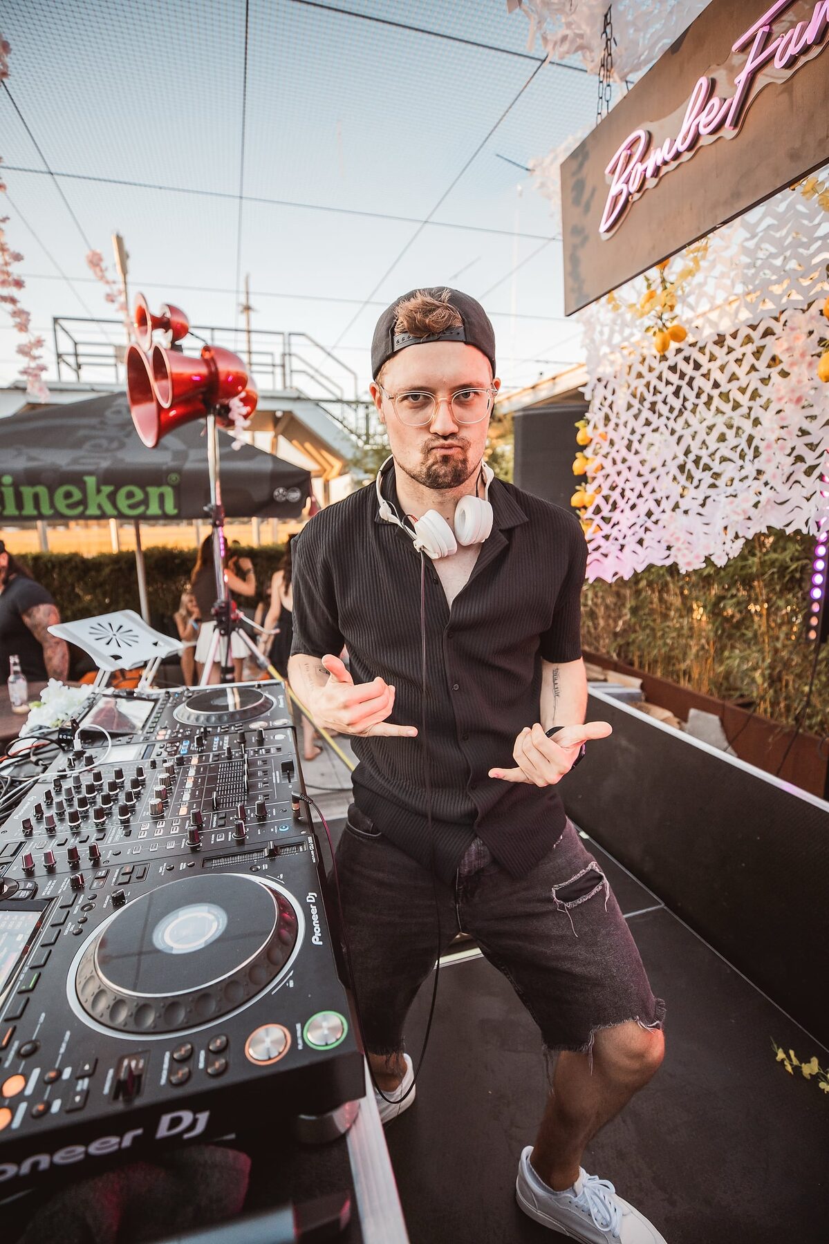 It's MA posiert am DJ-Pult neben dem Bombe-Family-Logo
